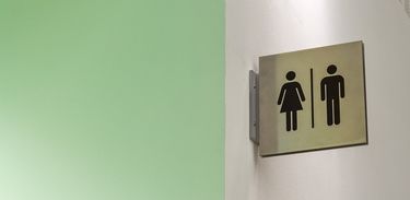 Uma placa com indicação de banheiros masculino e feminino