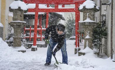 Homem limpa a neve na frente de templo em Tottori, Japão