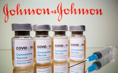Frascos rotulados como de vacina contra Covid-19 em frente ao logo da Johnson & Johnson em foto de ilustração
