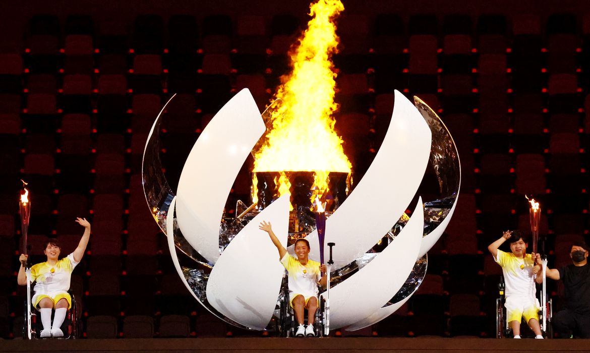 Atletas acendem tochas olímpicas na inaguração dos jogos de Tóquio 2020.