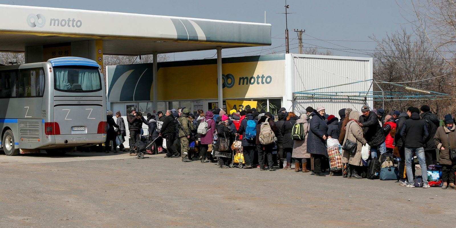 Evacuees wait for a bus before leaving the city of Mariupol