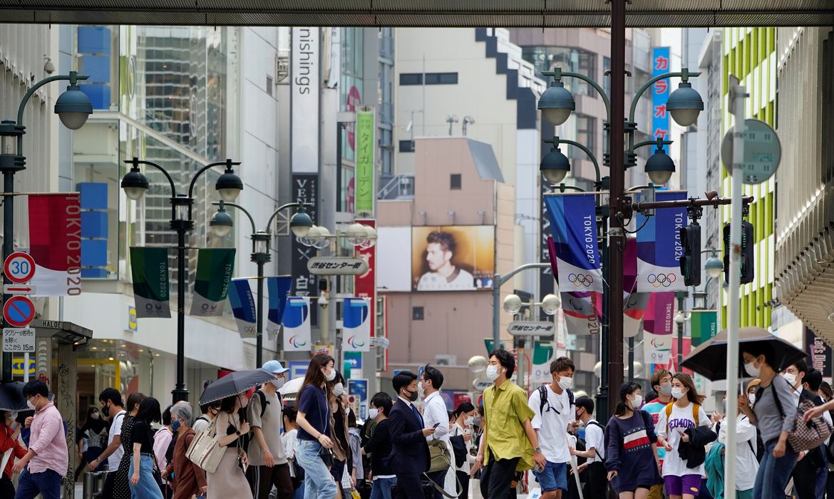 Pedestres usam máscaras de proteção enquanto caminham sob rua decorada para os Jogos Olímpicos e Paralímpicos da Tóquio-2020 no Japão - anéis - transeuntes - Olimpíada