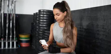 Mulher usa celular em uma academia 