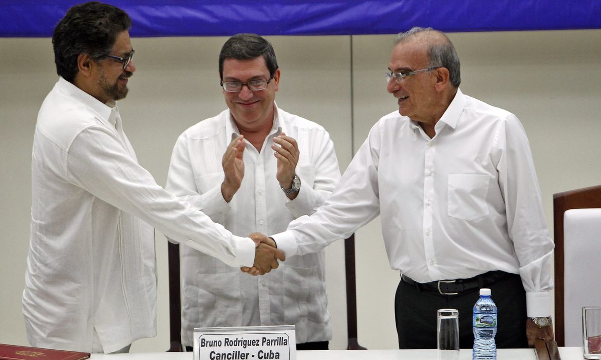 O número dois das Farcs, Luciano Marín, também conhecido como Iván Márquez, e o ex-vice-presidente da Colômbia, Humberto de la Calle, apertam as mãos após assinar acordo histórico em Havana 