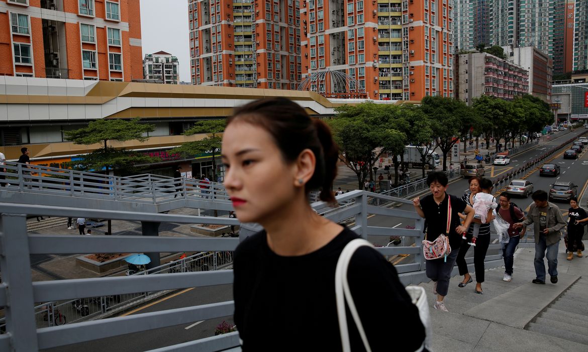 FILE PHOTO: People walk past newly built residential flats in Shenzhen, Guangdong Province, China October 26, 2019. REUTERS/Tyrone Siu/File Photo