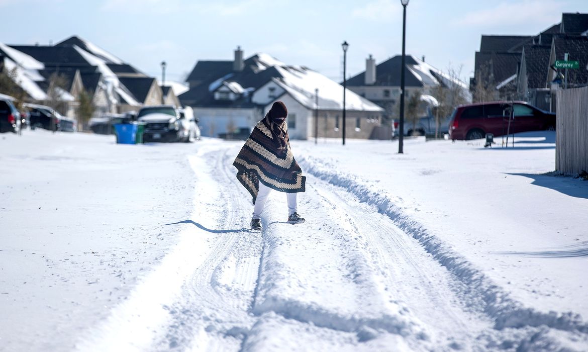 A man walks to his friend's home in a neighbourhood without electricity as snow covers the BlackHawk neighborhood in Pflugerville