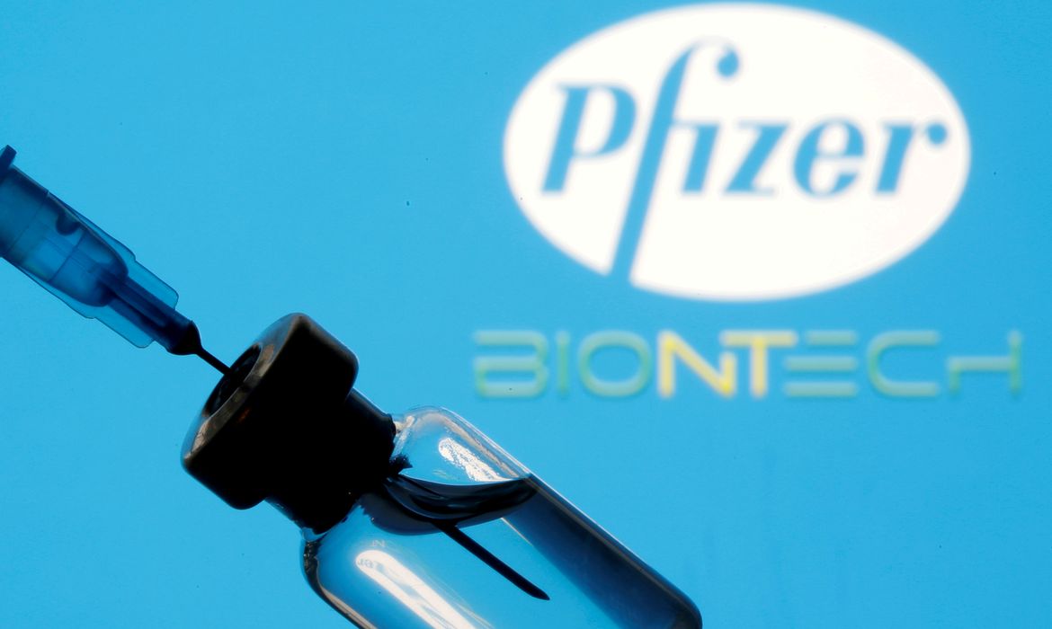 Frasco e seringa em frente aos logos da Pfizer e da BioNTech em foto de ilustração