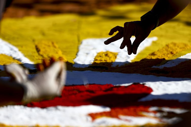 Marcelo Camargo/Agência Brasil Fiéis confeccionam os tradicionais tapetes de serragem durante a Festa de Corpus Christi de Brasília, que retorna à Esplanada dos Ministérios após 2 anos de celebrações reduzidas por conta da pandemia.