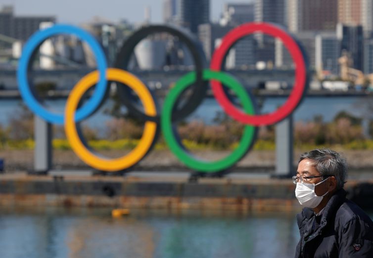 Reuters/Stoyan Nenov/Direitos Reservados Homem usando máscara de proteção em Tóquio por temor do coronavírus próximo a anéis dos Jogos de Tóquio 2020