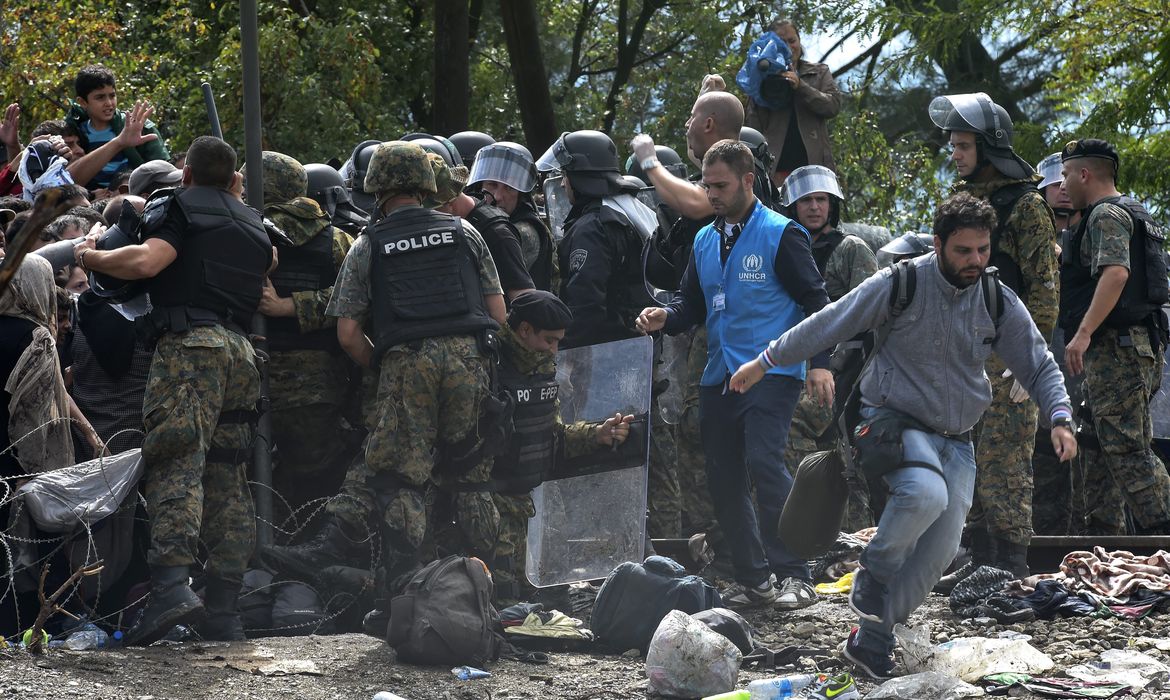 Refugiados do lado da Grécia furam bloqueio policial na fronteira com a Macedônia para alcançarem o norte da Europa
