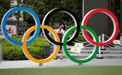 Anéis olímpicos em frente a Estádio Nacional de Tóquio