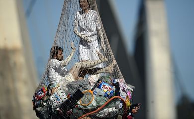 Artistas pendurados em rede com lixo durante performance artística em Brasília (Marcello Casal/Agência Brasil)