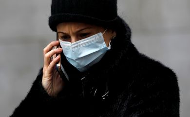 FILE PHOTO: A woman in a surgical mask uses her cellphone after more cases of coronavirus were confirmed in Manhattan, New York City, New York