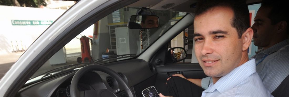 O securitário Flávio Oliveira usa o smartphone para acessar e-mails de trabalho enquanto dirige