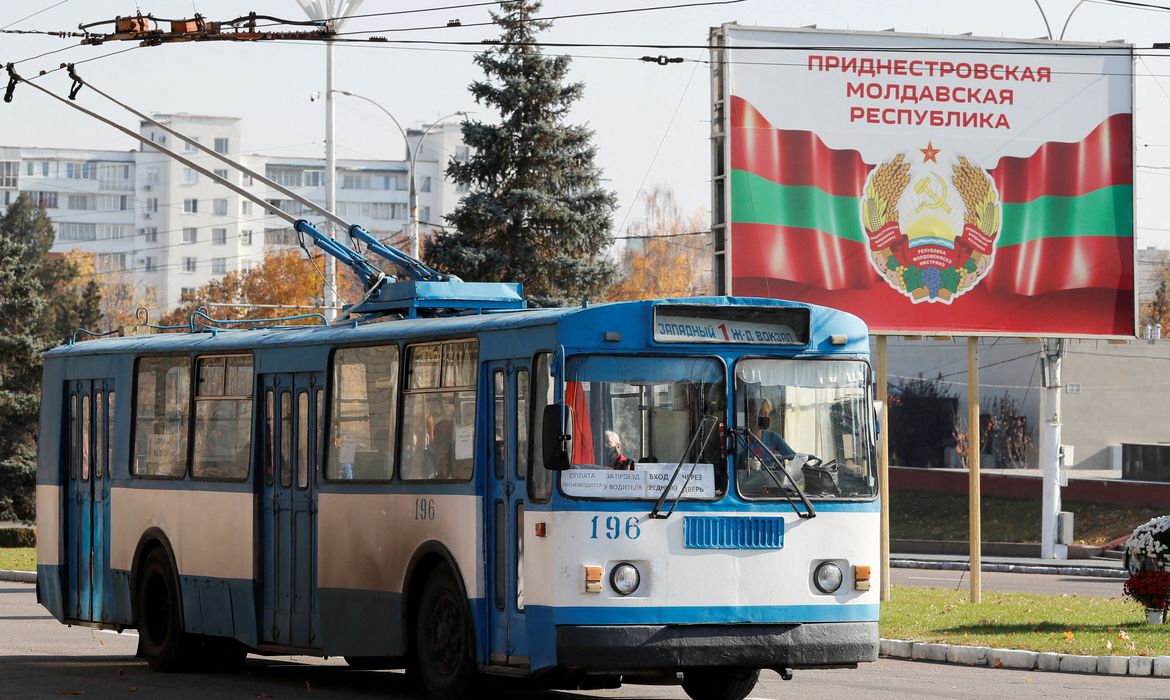 Trolêbus perto de pôster com brazão oficial de armas em Tiraspol, na região separatista da Transnístria, na Moldávia