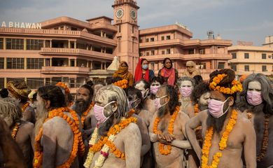 Naga Sadhus, or Hindu holy men wearing face masks wait before the procession for taking a dip in the Ganges river during Shahi Snan at 