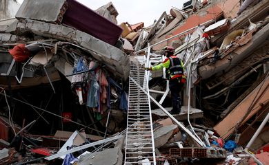 Agente de resgate nos destroços de prédio destruído por terremoto em Kirikhan, na Turquia