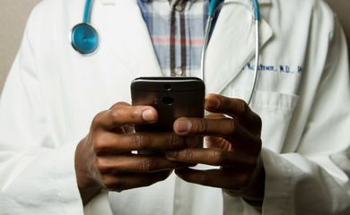 Médico com estetoscópio fala no celular. Foto: National Cancer Institute/Unsplash