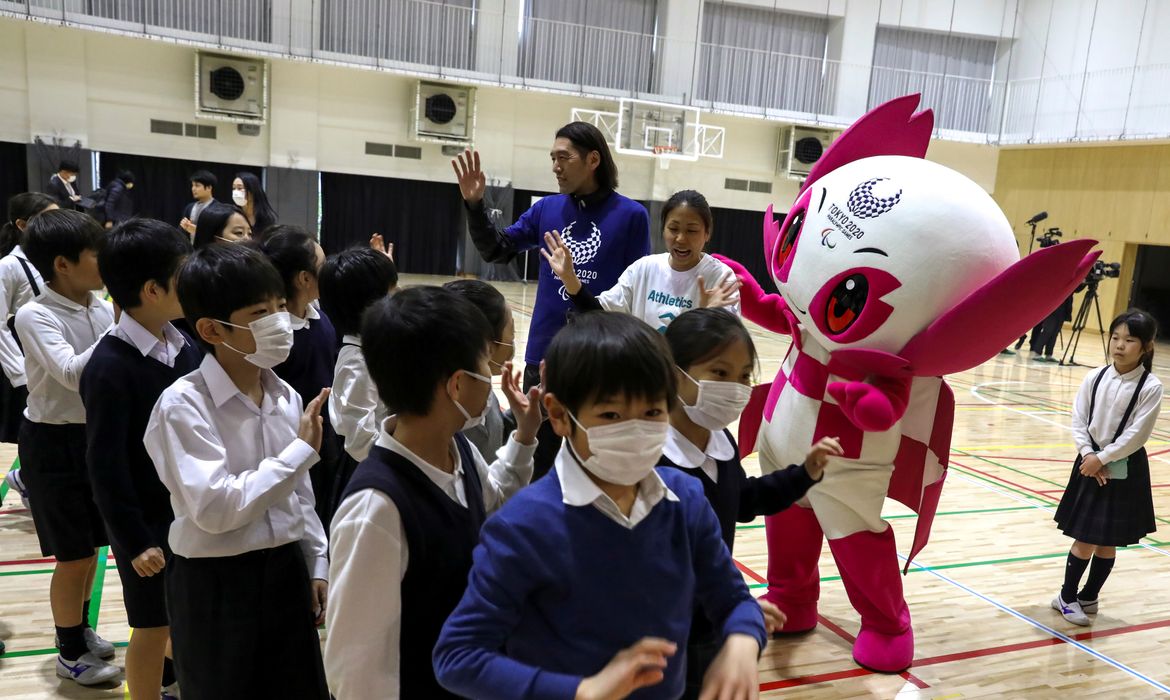 Crianças usando máscara de proteção de coronavírus brincam com mascote dos Jogos ParalímpicosParalympic Games in