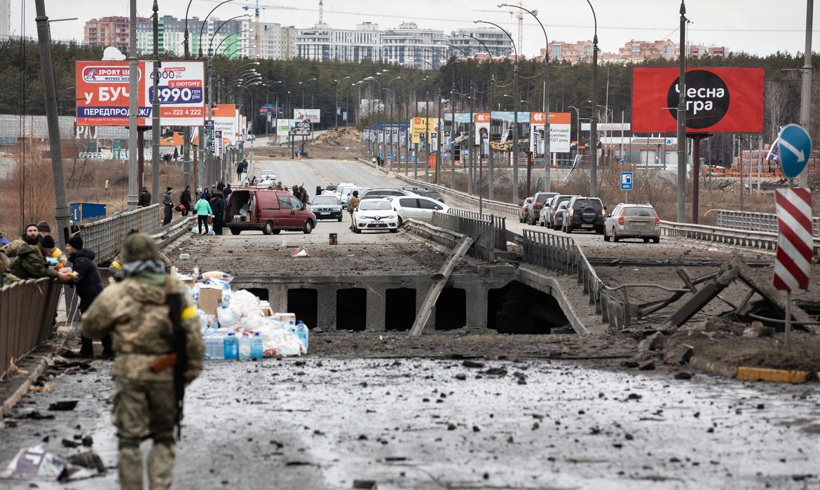 Pessoas fugindo da invasão russa à Ucrânia cruzam ponte destruída na região de Kiev