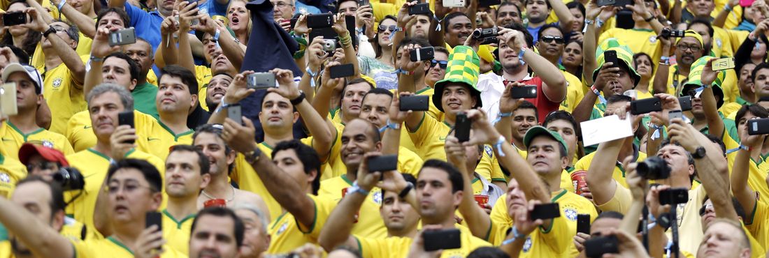 Com seus celulares, torcedores do Brasil registram cada momento da partida contra Camarões no Estádio Mané Garrincha, em Brasília