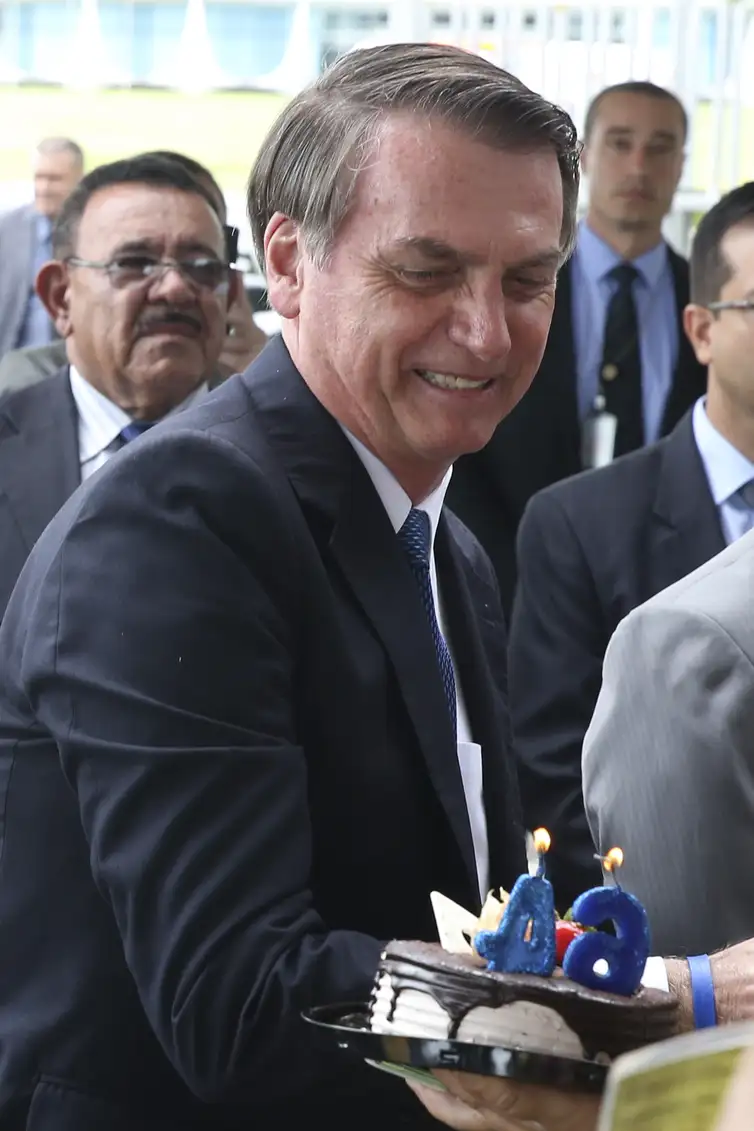 No dia do seu aniversário de 64 anos, o presidente Jair Bolsonaro,recebe um bolo e cumprimenta populares na saída do Palácio da Alvorada.