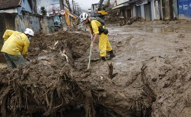 Equipes de guarda-parques trabalham na desobstrução da Rua Teresa, bloqueada pela lama acumulada de deslizamentos de terra das chuvas em Petrópolis.
