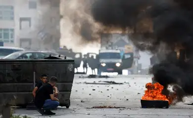 Soldados israelenses perto de veículos militares enquanto palestinos se abrigam perto de pneus em chamas durante ação de forças israleneses na Cisjordânia ocupada
07/10/2024
Reuters/MohamadTorokman/Proibida reprodução