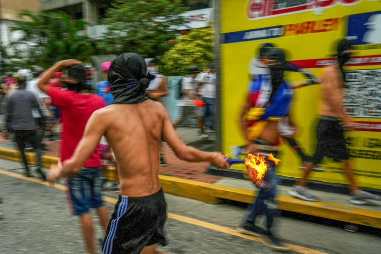 A protester runs with a Molotov cocktail as Venezuelan opposition supporters protest following the announcement by the National Electoral Council that Venezuela's President Nicolas Maduro won the presidential election, in Caracas, Venezuela July 29, 2024. REUTERS/Alexandre Meneghini