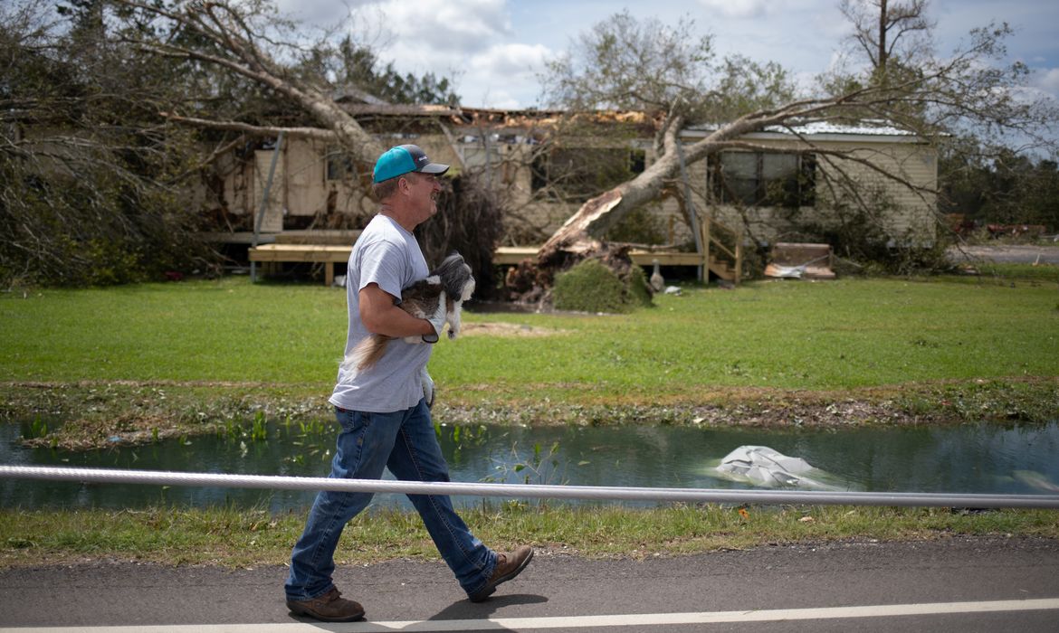Um residente local Clint Pippen segura seu cachorro Barkley enquanto ele passa por linhas de transmissão para chegar a sua residência após o furacão Laura em Sulphur, Louisiana, EUA, 27 de agosto de 2020. REUTERS / Adrees Latif