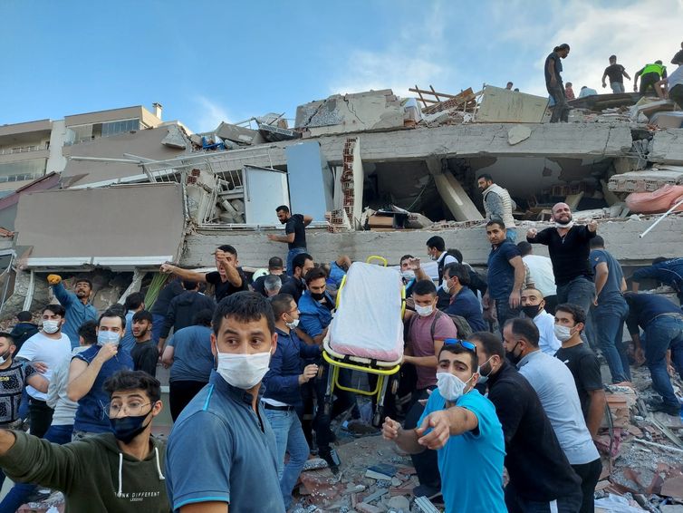 Moradores e oficiais procuram sobreviventes em um prédio desabado em Izmir