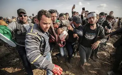 Palestinos ajudam jovem companheiro que morreu durante os enfrentamentos com as tropas do Exército israelense na Faixa de Gaza (Mohammed Saber/Agência EFE/direitos reservados)