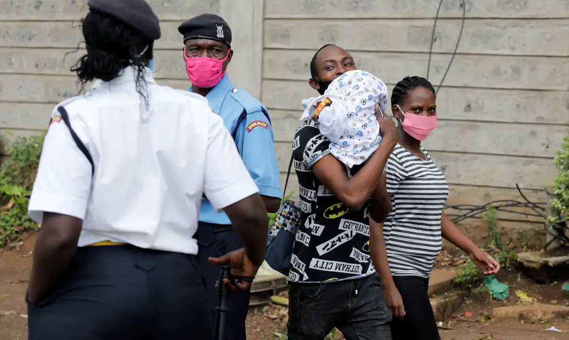Casal carregando bebê caminha perto de posto de controle policial em Nairóbi