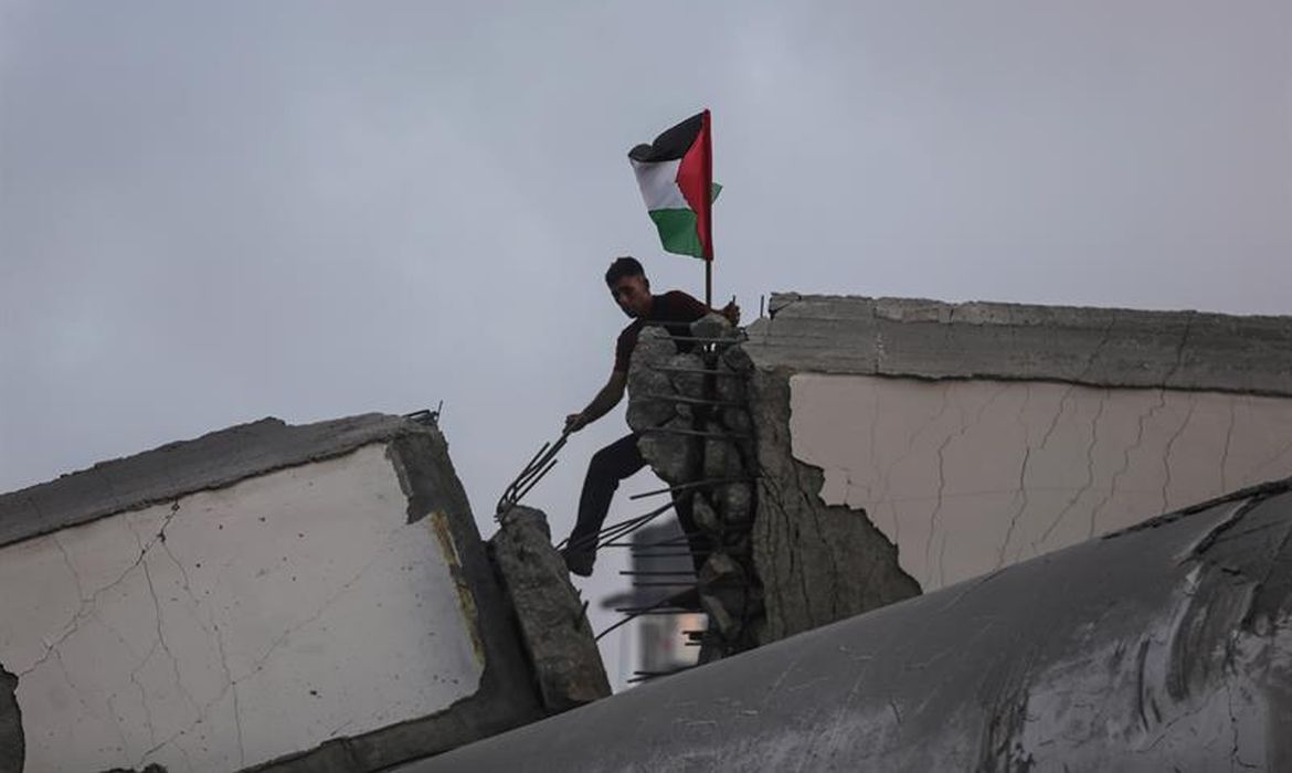 Grupo de palestinos inspeciona restos de um centro cultural destruído por un ataque aéreo israelense em Gaza