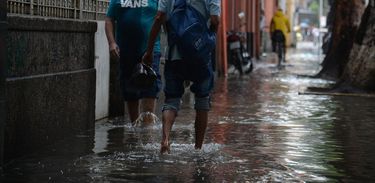 Moradores caminham em água de enxurrada no RJ