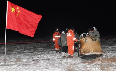Researchers work around Chang'e-5 lunar return capsule carrying moon samples next to a Chinese national flag, after it landed in northern China's Inner Mongolia Autonomous Region