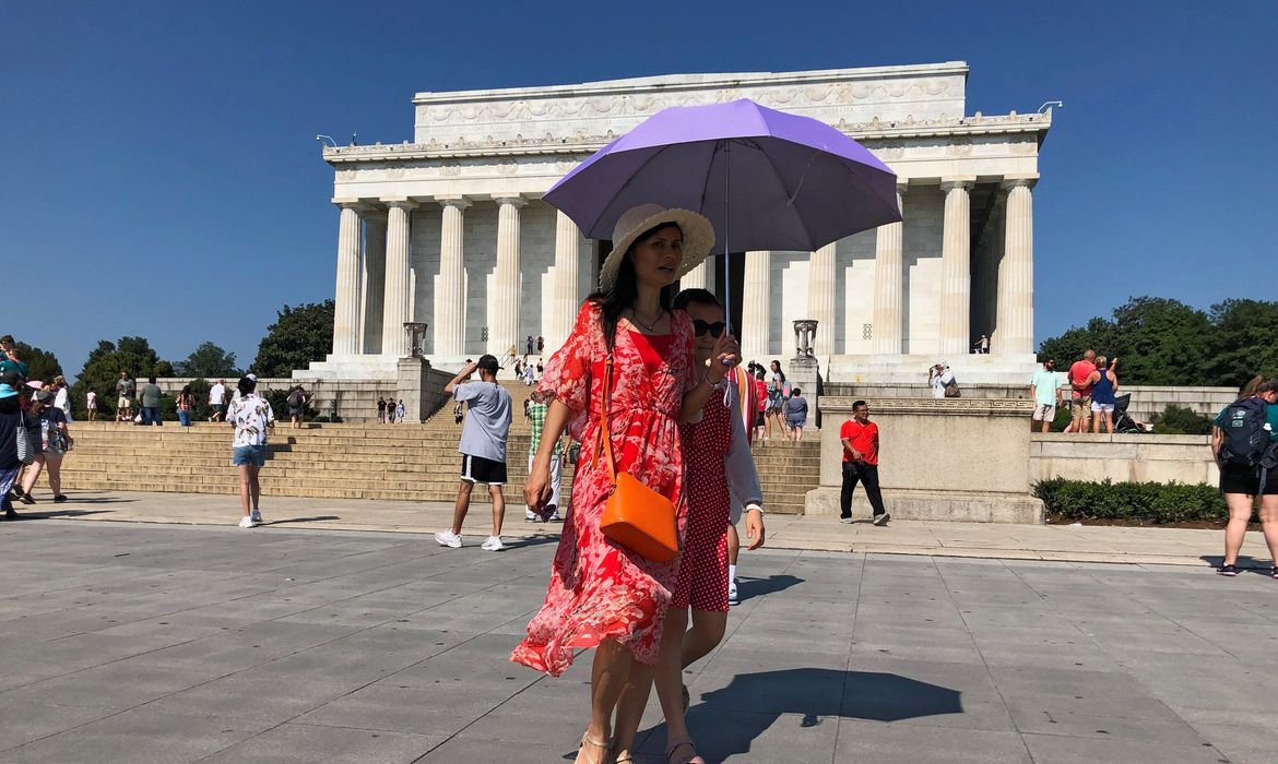 Turista se protege do sol usando um guarda-chuva em frente ao Lincoln Memorial, em dia de forte calor em Washington, EUA.