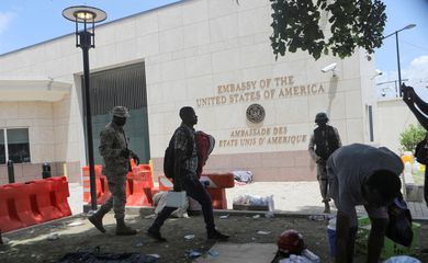 Homem carrega seus pertences após polícia usar gás lacrimogêneo para dispersar pessoas acampadas em frente à embaixada dos Estados Unidos em Porto Príncipe, no Haiti