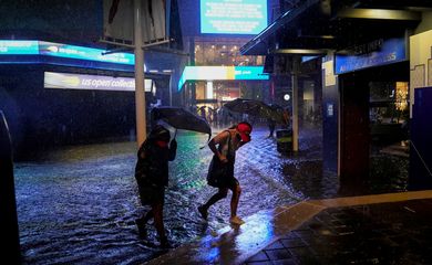 Espectadores atravessam área inundada perto do estádio Louis Armstrong, no complexo onde é disputado o Aberto dos EUA de tênis, em Nova York