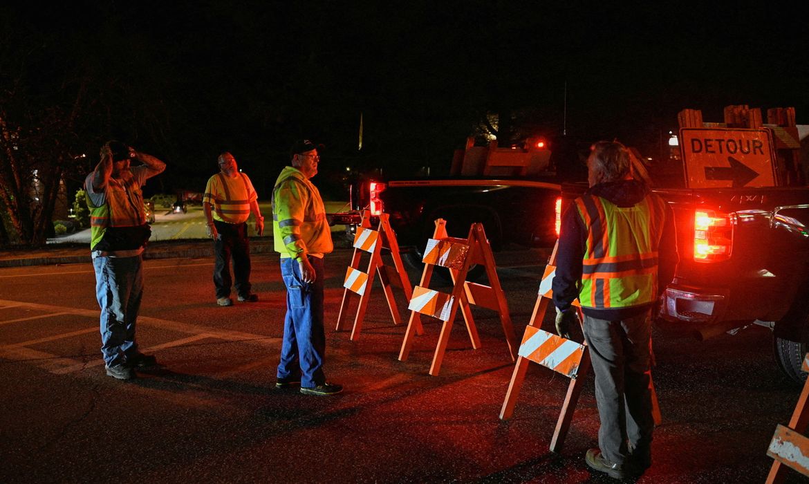 Workers set down detour signs while police organize around Lisbon High School as an active search for a gunman is underway after Lewiston's deadly mass shootings, in Lisbon, Maine, U.S. October 26, 2023.  REUTERS/Nicholas Pfosi REFILE - CORRECTING CITY FROM 