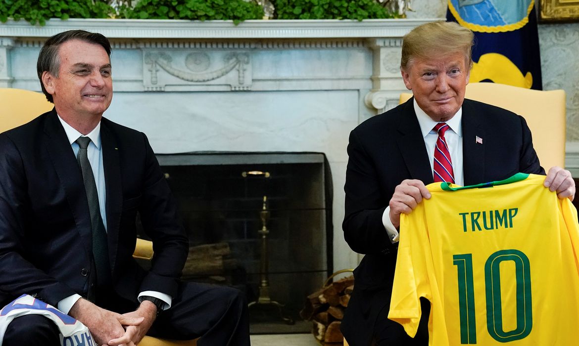 O presidente do Brasil, Jair Bolsonaro, dá uma camiseta da Seleção Brasileira de futebol para o presidente dos EUA, Donald Trump, durante reunião no Salão Oval da Casa Branca, em Washington (EUA). 