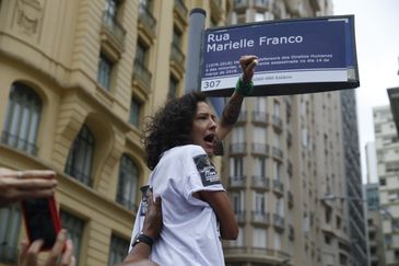 A viúva Mônica Benício com uma réplica de placa de Marielle Franco , em frente à Câmara, na Cinelândia, no dia em que o assassinato da vereadora completa sete meses.