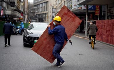 Funcionário monta barreiras em rua de Xangai para criar área isolada durante lockdown da Covid-19