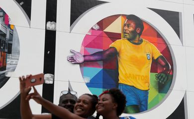 Fãs tiram foto em frente a mural de Pelé em Santos