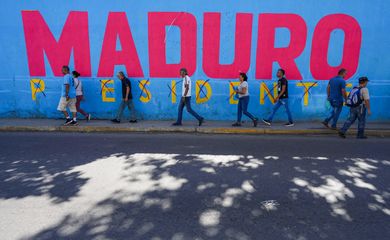 People pass by a mural saying 