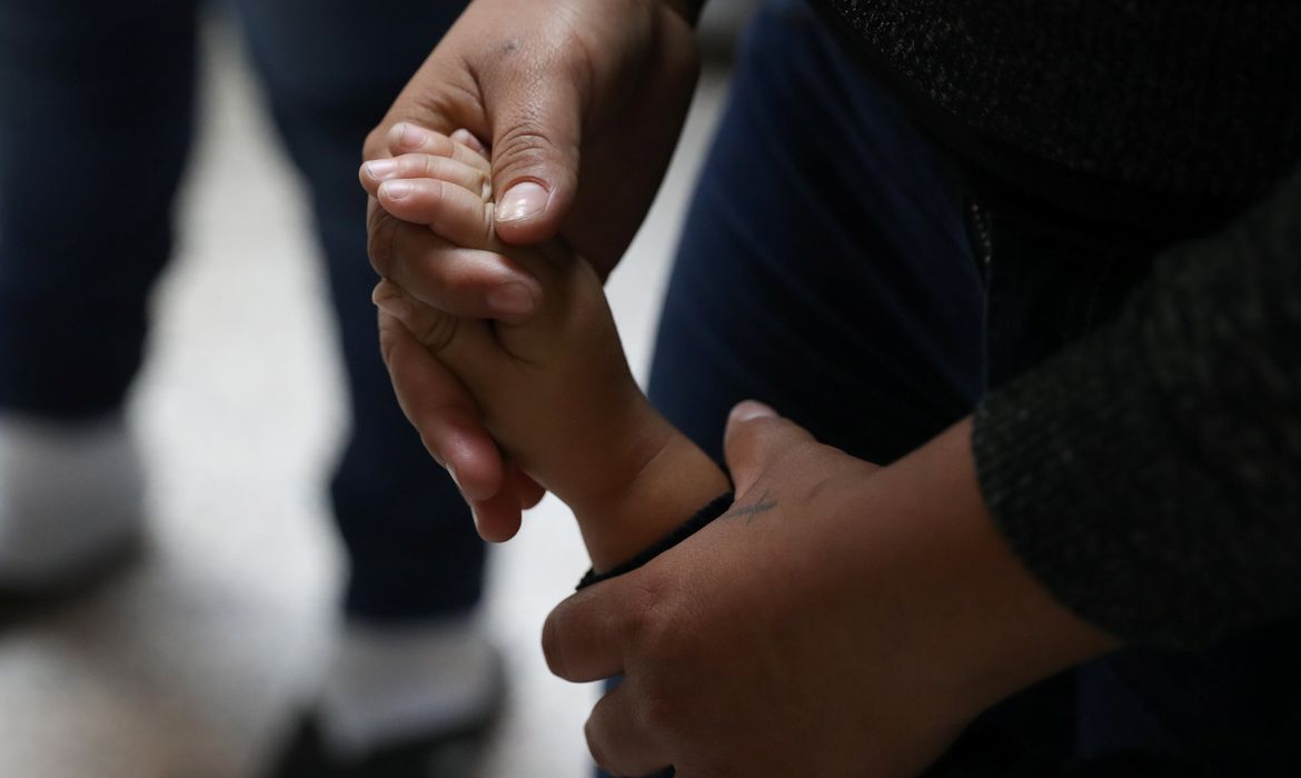 Uma mulher segura a mão de uma criança enquanto famílias de imigrantes ilegais são libertadas da detenção no Texas, nos Estados Unidos 