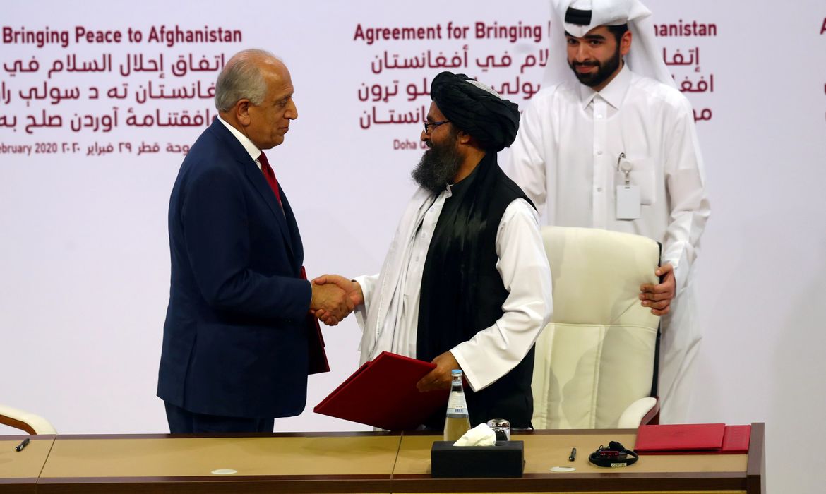 REUTERS/Ibraheem Al Omari/Direitos reservados Mullah Abdul Ghani Baradar, the leader of the Taliban delegation, and Zalmay Khalilzad, U.S. envoy for peace in Afghanistan, shake hands after signing agreement at ceremony between members of Afghanistan's Taliban and the U.S. in Doha
