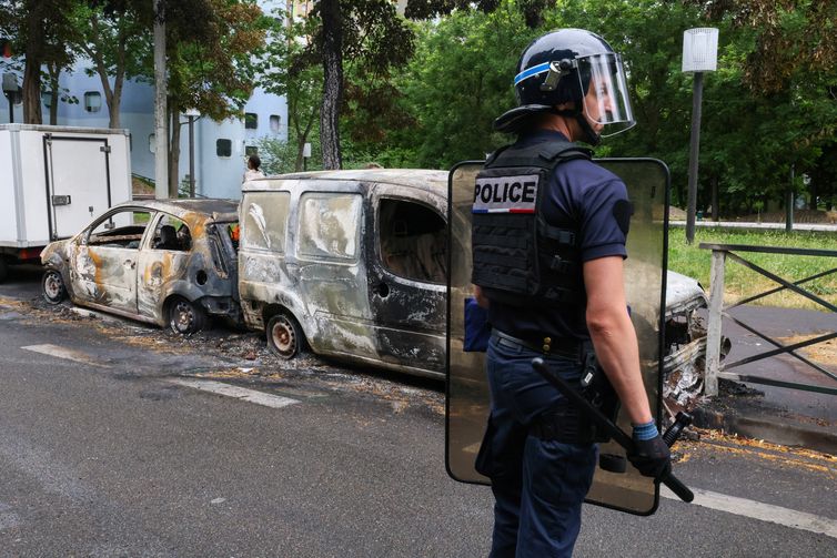 Um policial francês faz guarda ao lado de veículos queimados durante uma noite de confrontos entre manifestantes e policiais, após a morte de um adolescente de 17 anos morto por um policial francês durante uma parada de trânsito, em Nanterre, subúrbio de Paris, França, em 1º de julho de 2023. REUTERS/Yves Herman