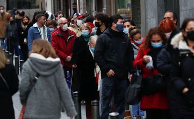 People wearing face masks queue to buy Christmas lottery tickets, in Madrid