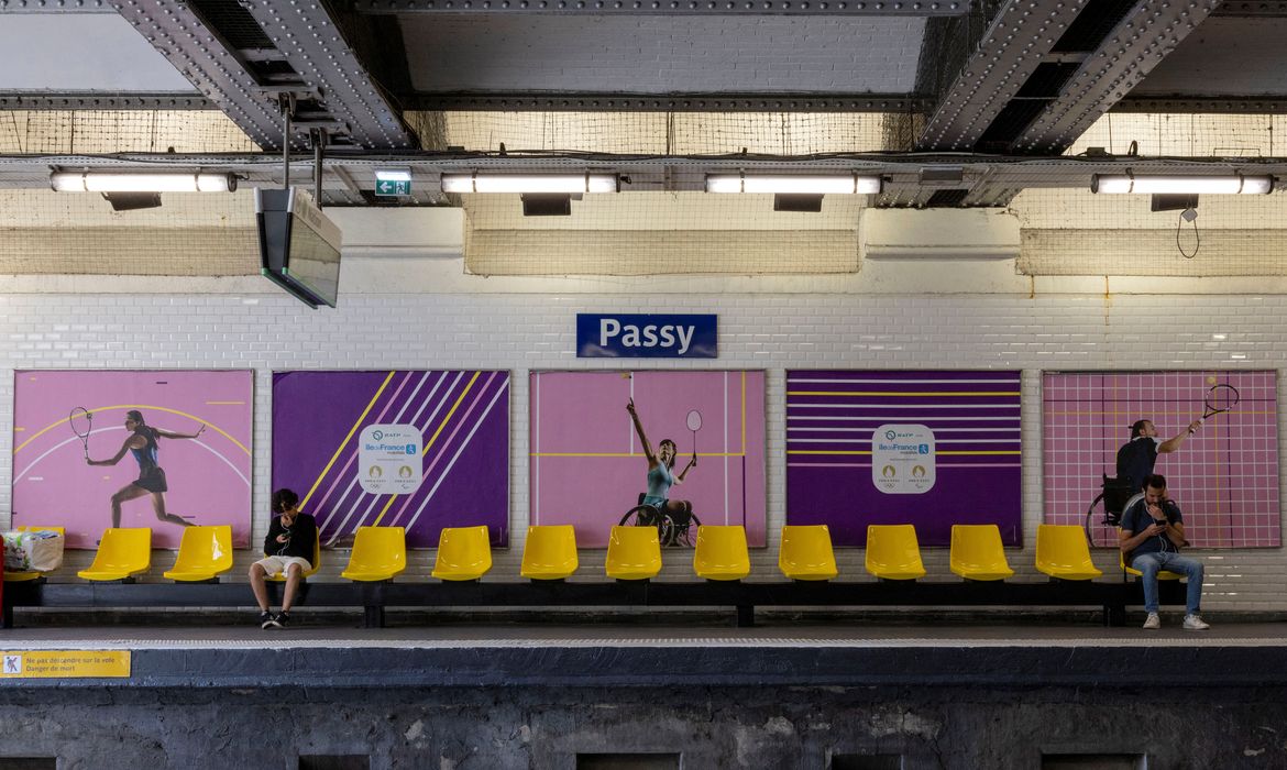 People sit in front of posters of Paralympic athletes at Passy metro station ahead of the Paris 2024 Summer Paralympic Games in Paris, France, August 27, 2024. REUTERS/Umit Bektas